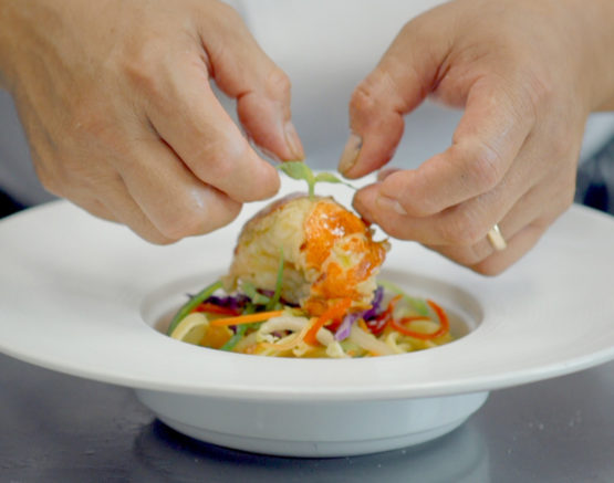 chef's hands garnishing appetizer